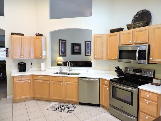 kitchen with a sink, stainless steel appliances, light tile patterned floors, and light countertops