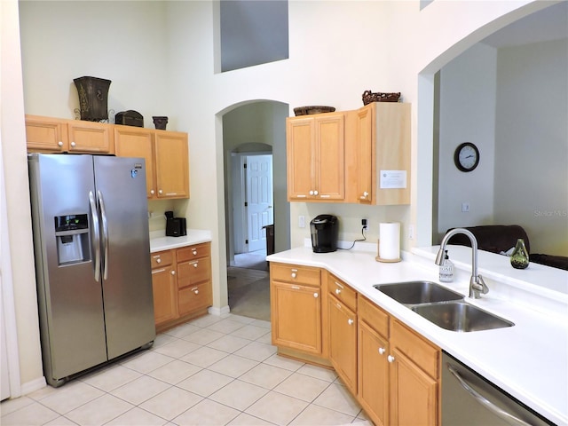 kitchen featuring a sink, stainless steel appliances, arched walkways, and light countertops