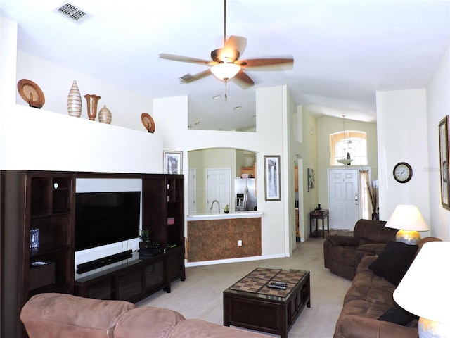 living room featuring ceiling fan, visible vents, vaulted ceiling, and light colored carpet