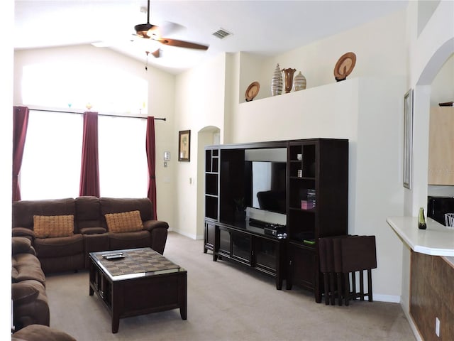 living area featuring arched walkways, light colored carpet, visible vents, ceiling fan, and high vaulted ceiling