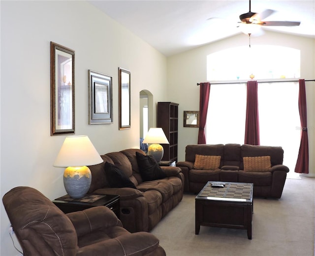 living room with arched walkways, vaulted ceiling, a ceiling fan, and light colored carpet