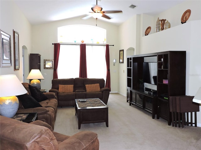 living area featuring light carpet, visible vents, arched walkways, and a ceiling fan