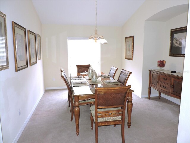 dining space featuring an inviting chandelier, baseboards, vaulted ceiling, and light colored carpet