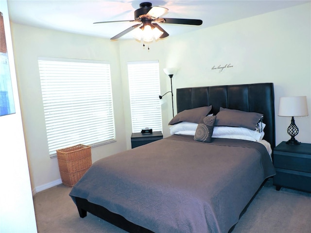 bedroom with a ceiling fan, light carpet, and baseboards