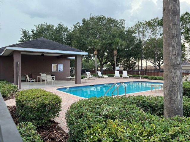 pool featuring a patio area, ceiling fan, and fence