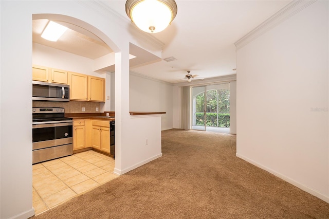 kitchen with crown molding, appliances with stainless steel finishes, and light colored carpet