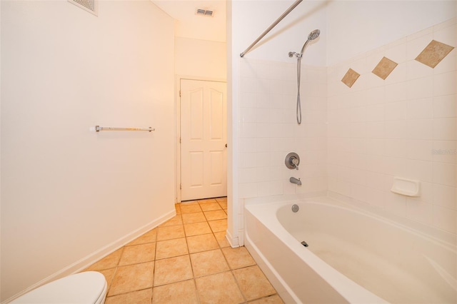 bathroom featuring tile patterned flooring, toilet, and tiled shower / bath