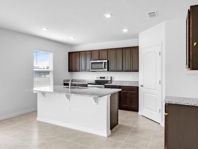 kitchen with light tile patterned floors, appliances with stainless steel finishes, sink, and a center island with sink