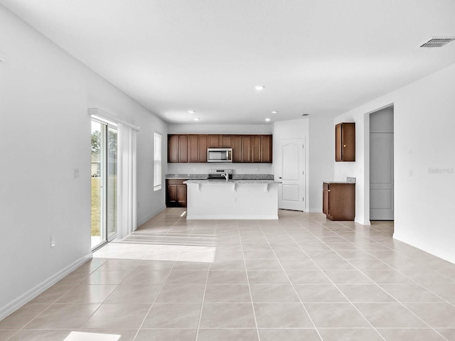 kitchen with a kitchen island with sink, light tile patterned floors, and range