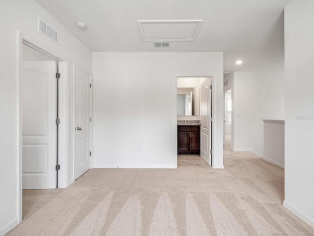 unfurnished bedroom featuring light colored carpet and ensuite bathroom