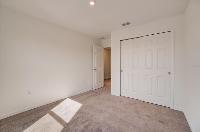 unfurnished bedroom featuring light colored carpet and a closet