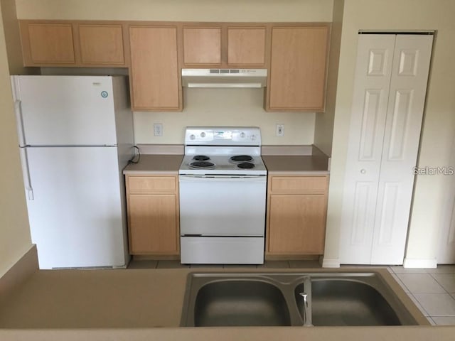 kitchen featuring light brown cabinets and white appliances