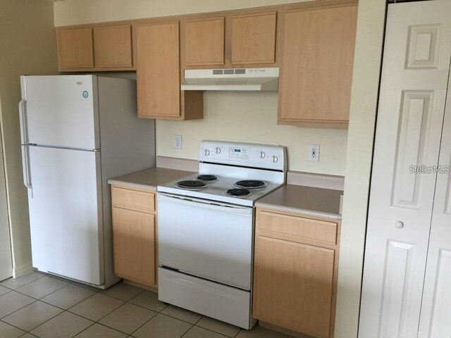 kitchen with light brown cabinetry, white appliances, and light tile patterned floors