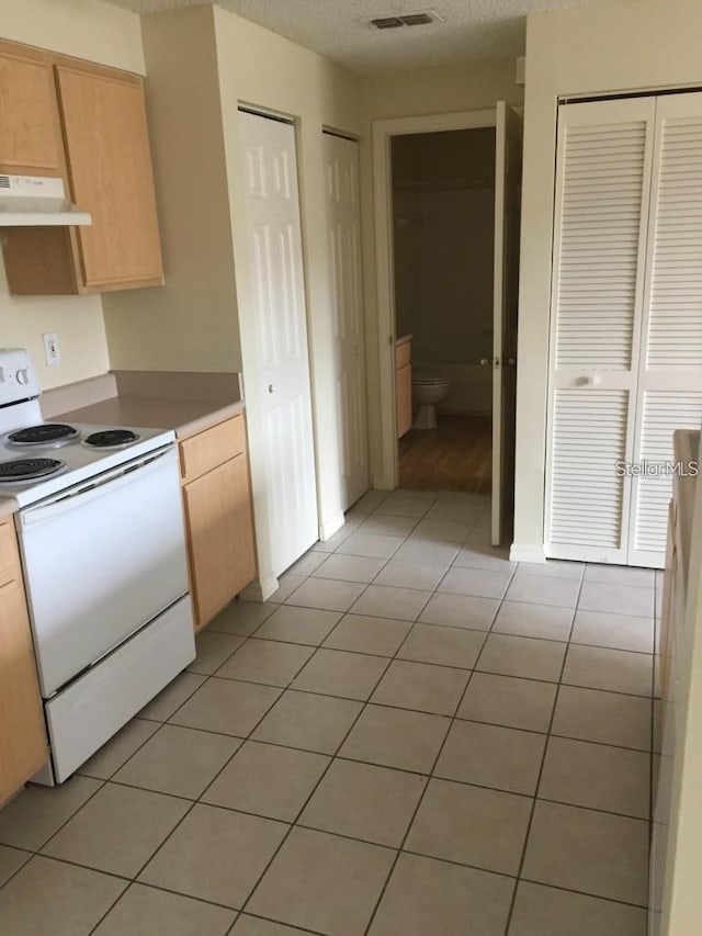 kitchen featuring light tile patterned floors, white range with electric stovetop, and light brown cabinetry