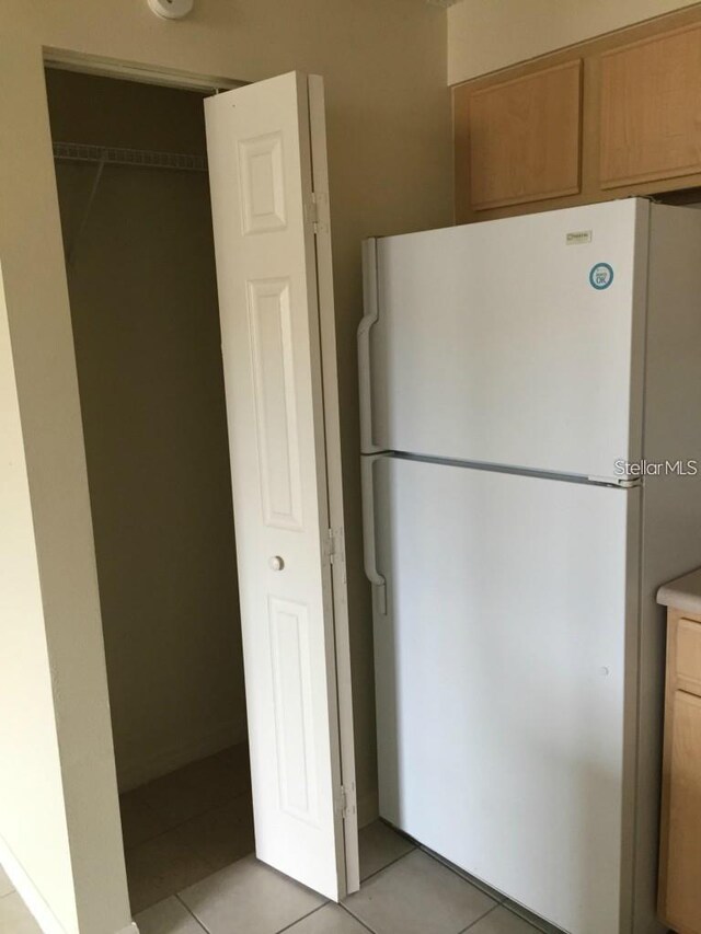 kitchen with light tile patterned flooring and white fridge