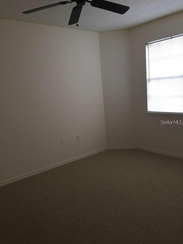 carpeted spare room with ceiling fan and a textured ceiling