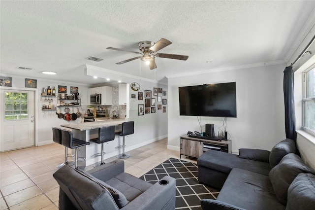 living room with sink, crown molding, a textured ceiling, light tile patterned floors, and ceiling fan