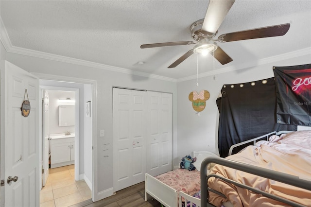 tiled bedroom featuring ceiling fan, a closet, a textured ceiling, and crown molding