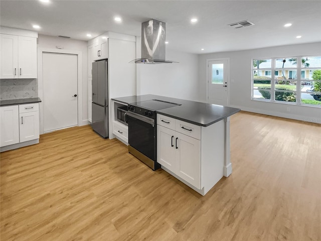 kitchen with dark countertops, freestanding refrigerator, island exhaust hood, and open floor plan