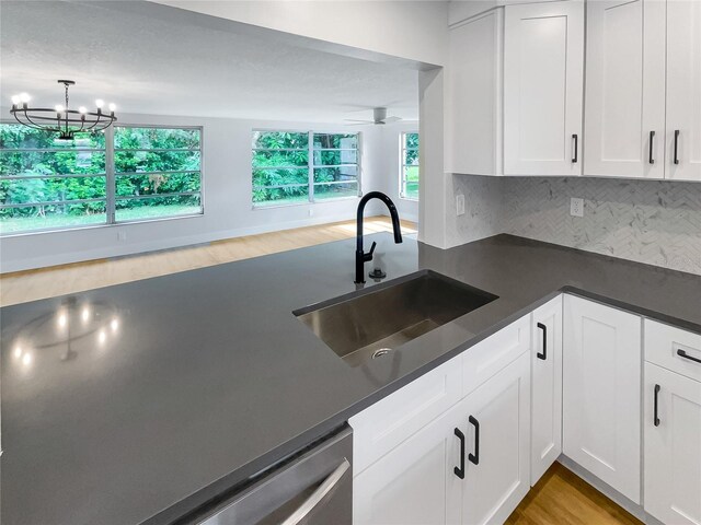 kitchen with decorative backsplash, dark countertops, a sink, and white cabinets