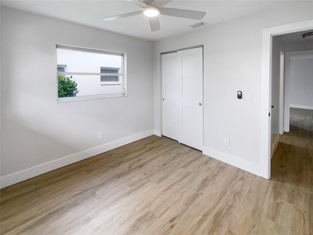 unfurnished bedroom featuring light wood-type flooring, baseboards, and a closet