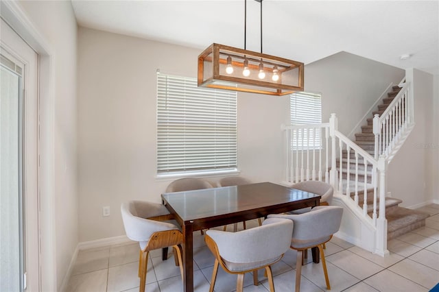 dining area with light tile patterned floors, stairway, and baseboards