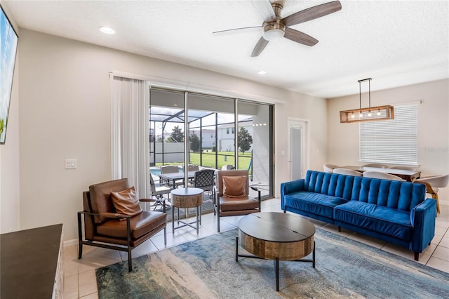 living area with a textured ceiling, light tile patterned flooring, recessed lighting, a sunroom, and a ceiling fan