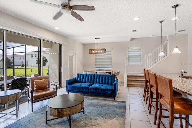 living area featuring stairs, light tile patterned floors, a textured ceiling, and visible vents