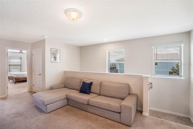 living area featuring baseboards, a textured ceiling, and light colored carpet