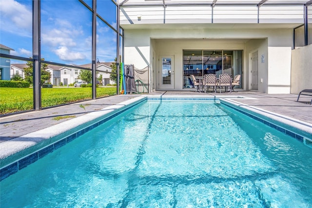 pool featuring glass enclosure, a patio, and a lawn