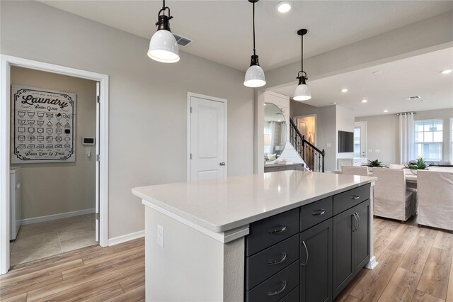 kitchen with light wood-type flooring, a center island, washer / clothes dryer, and pendant lighting