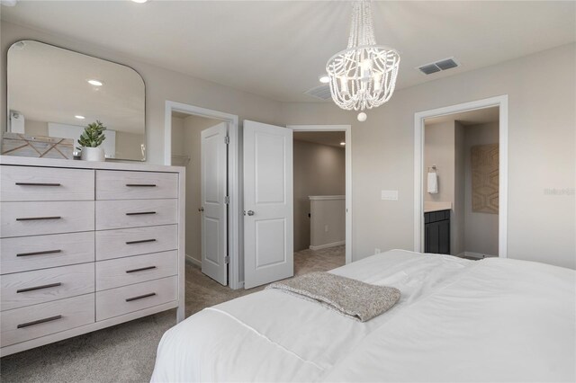 carpeted bedroom featuring an inviting chandelier and ensuite bathroom