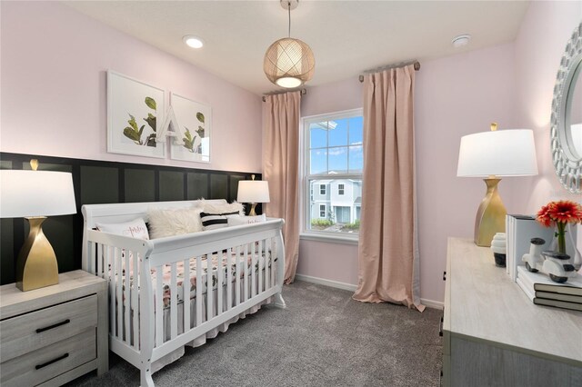 bedroom featuring a nursery area and dark carpet