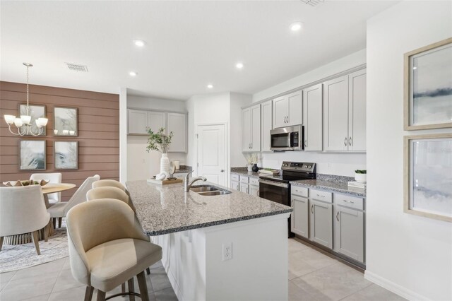 kitchen with dark stone counters, gray cabinetry, appliances with stainless steel finishes, light tile patterned floors, and sink