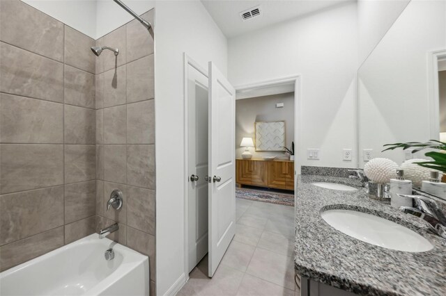 bathroom featuring tiled shower / bath combo, dual vanity, and tile patterned floors