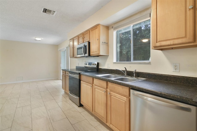 kitchen featuring sink, stainless steel appliances, a textured ceiling, and plenty of natural light