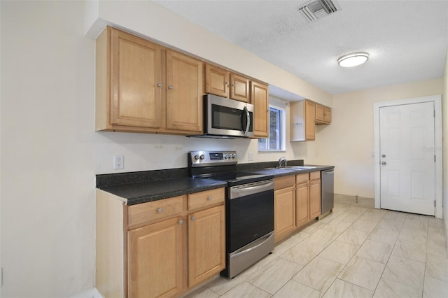 kitchen featuring sink, a textured ceiling, appliances with stainless steel finishes, and light tile patterned floors