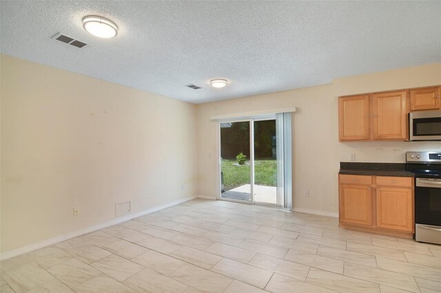 kitchen with light tile patterned floors, stainless steel appliances, and a textured ceiling