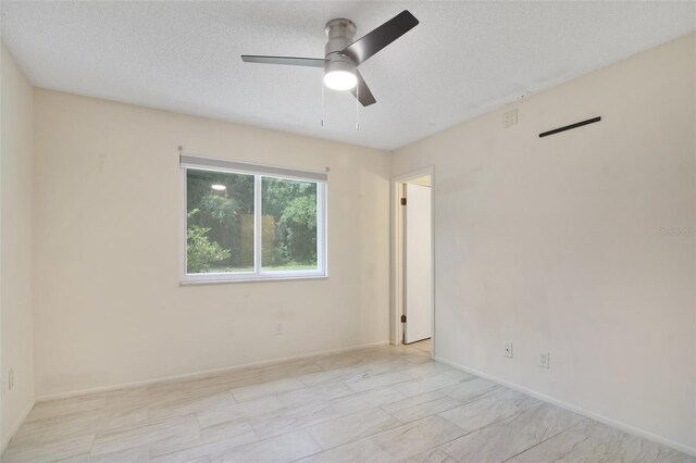 empty room featuring ceiling fan, a textured ceiling, and light tile patterned floors