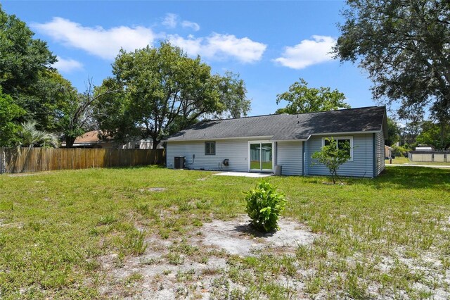 back of property featuring cooling unit and a yard