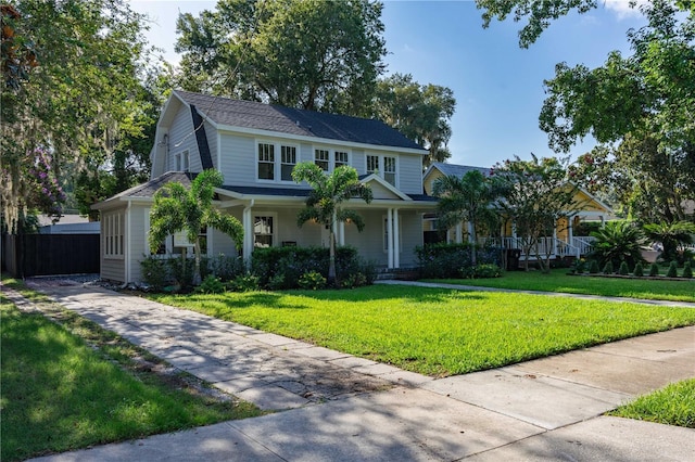 view of front facade with a porch, a front yard, and fence