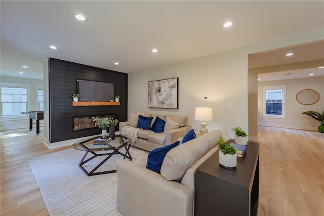 living room featuring light wood-style floors, a large fireplace, and recessed lighting