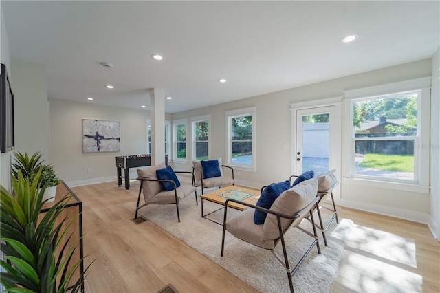 living area featuring baseboards, light wood-style floors, recessed lighting, and ornate columns