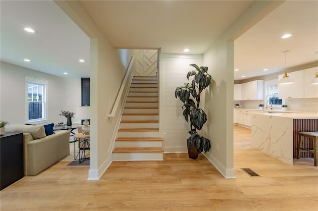 staircase featuring a healthy amount of sunlight, wood finished floors, and recessed lighting