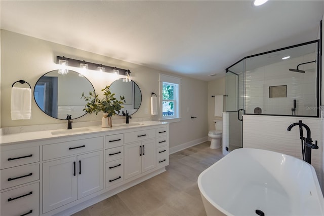 full bath featuring a freestanding tub, toilet, a sink, double vanity, and a stall shower