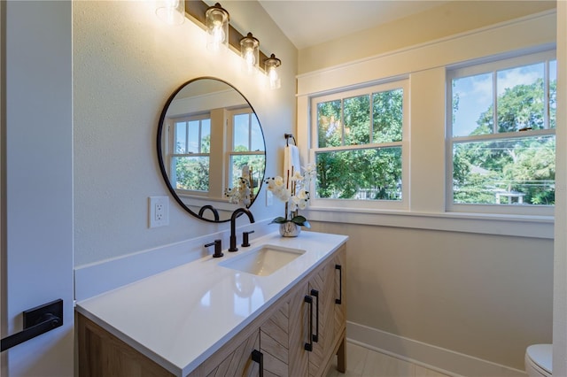 bathroom with toilet, vanity, and baseboards