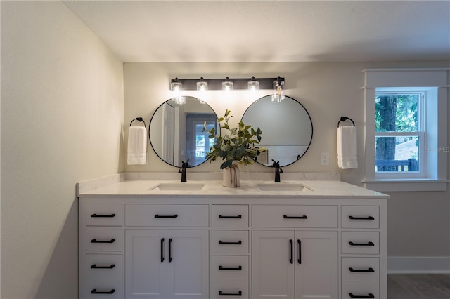 bathroom with a sink, baseboards, and double vanity