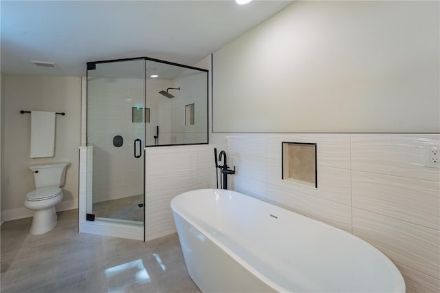 full bath with a freestanding tub, toilet, tile walls, visible vents, and a shower stall