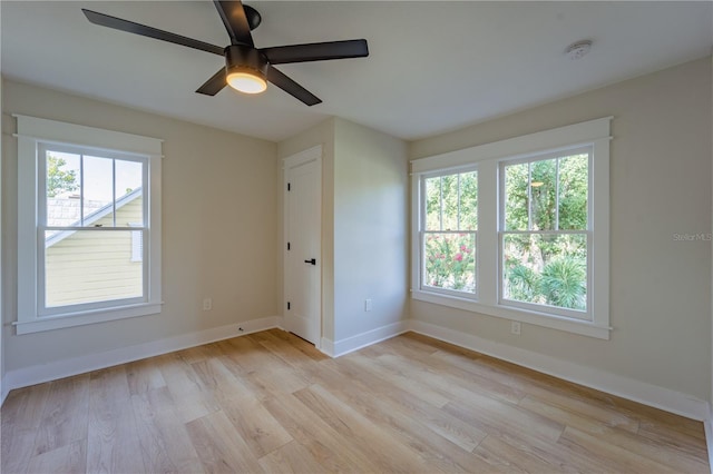 spare room featuring ceiling fan, light wood-type flooring, and baseboards