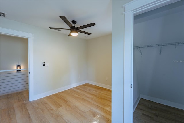 unfurnished bedroom featuring a ceiling fan, a closet, light wood-style flooring, and baseboards